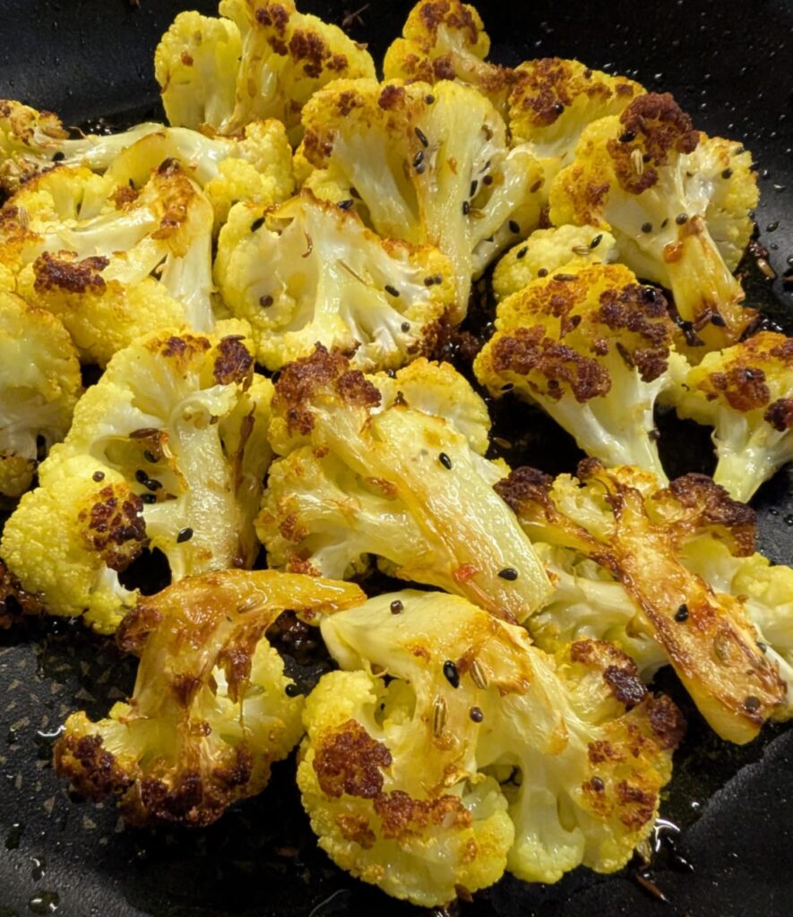 close up photo of turmeric roasted cauliflower florets with whole spices