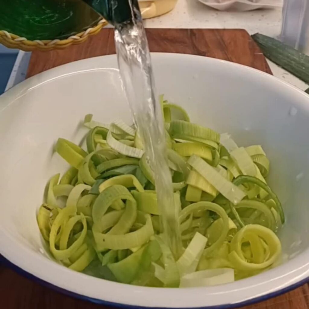 photo of water being poured onto sliced green evegtable in a white bowl