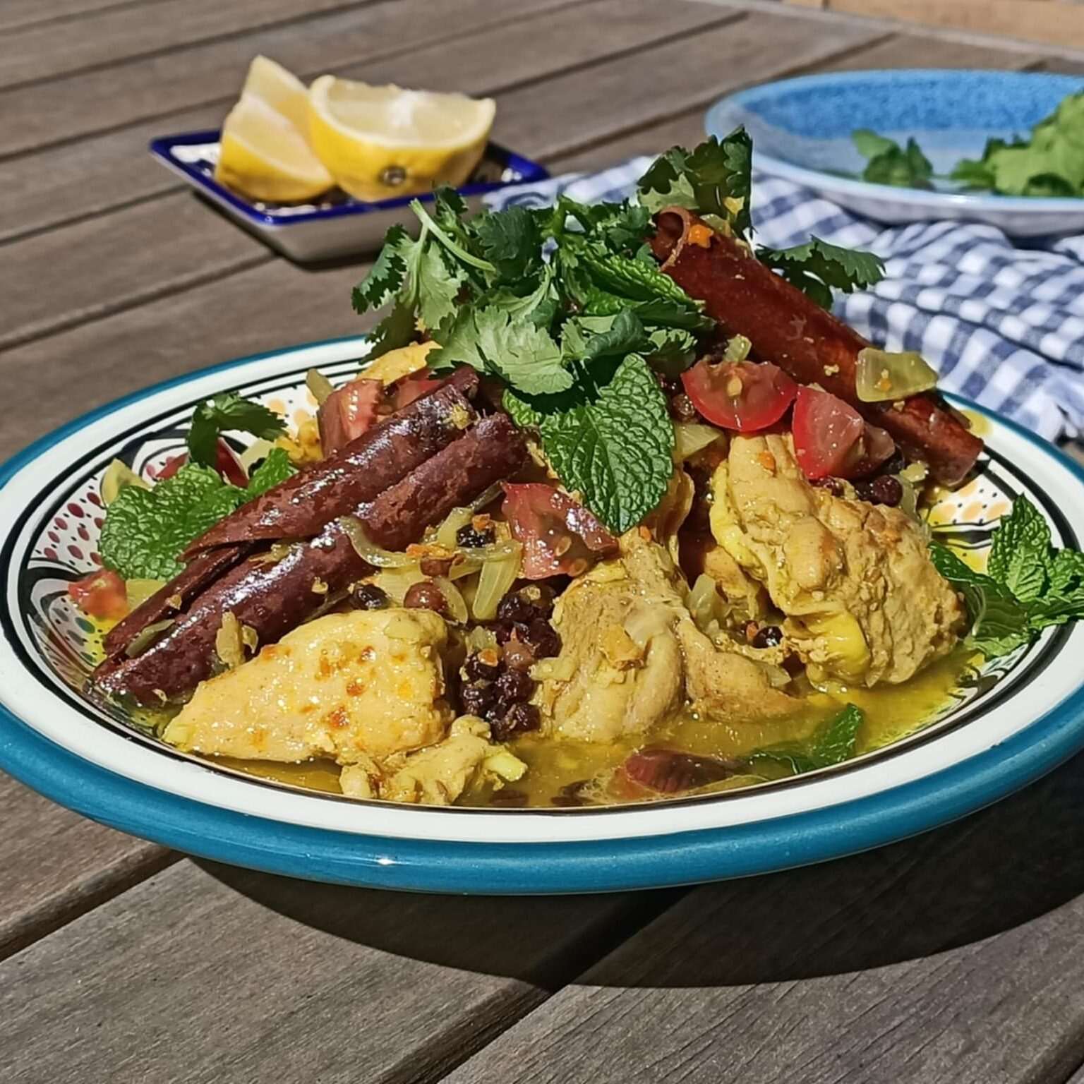 photo of a yellow meat dish topped with herbs and cinnamon on a wood table