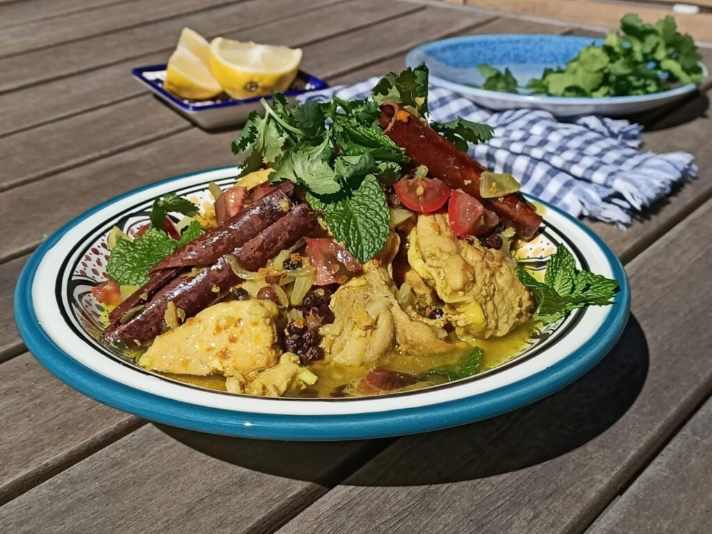 photo of a yellow meat dish topped with herbs and cinnamon on a wood table