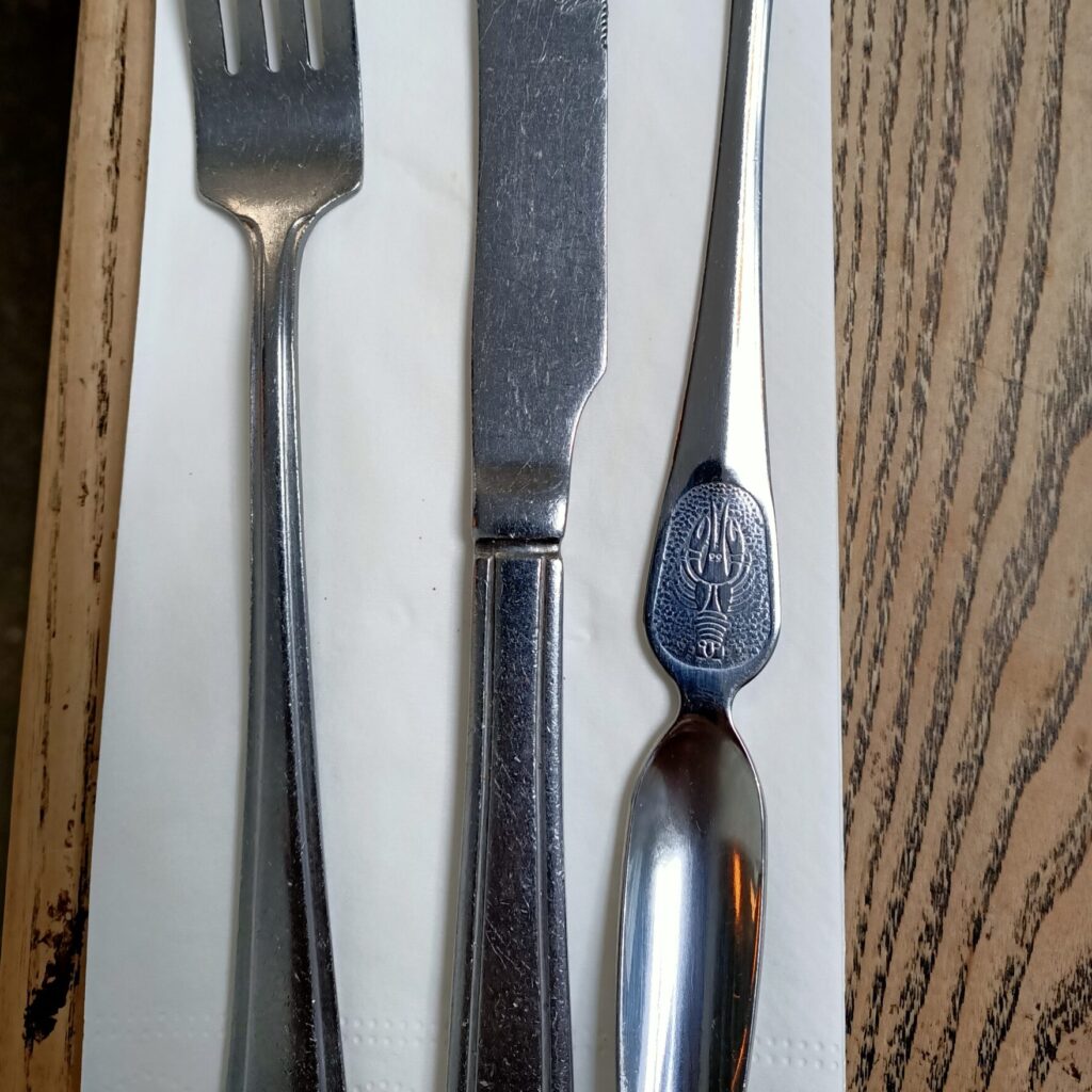 Photo of silver cutlery and white napkin on a wooden table