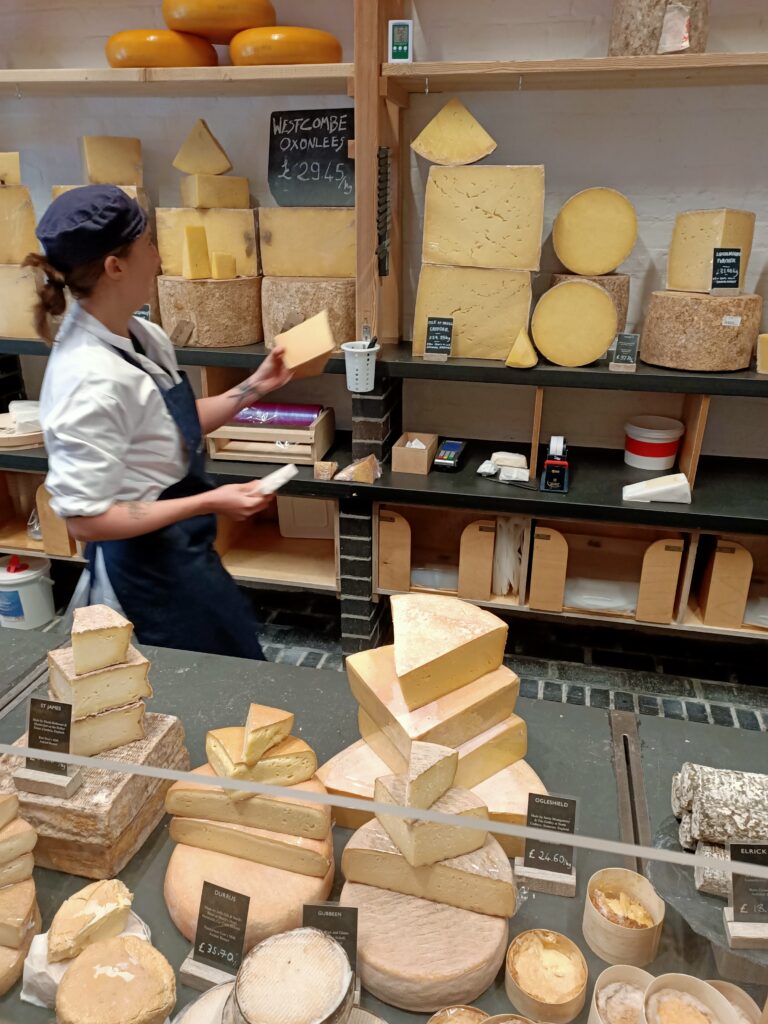 photo of a person in a cheese shop holding wedges of cheese