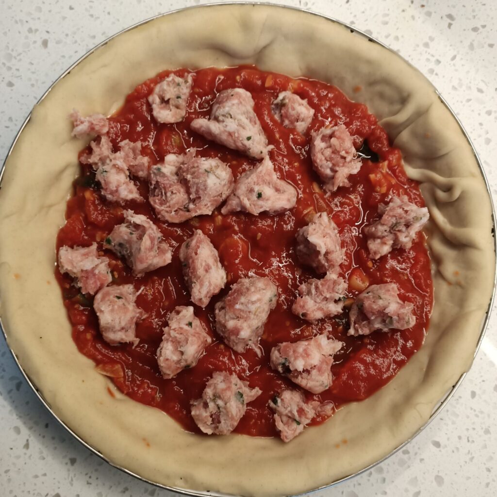 photo of a pie dish with tomato and bits of meat