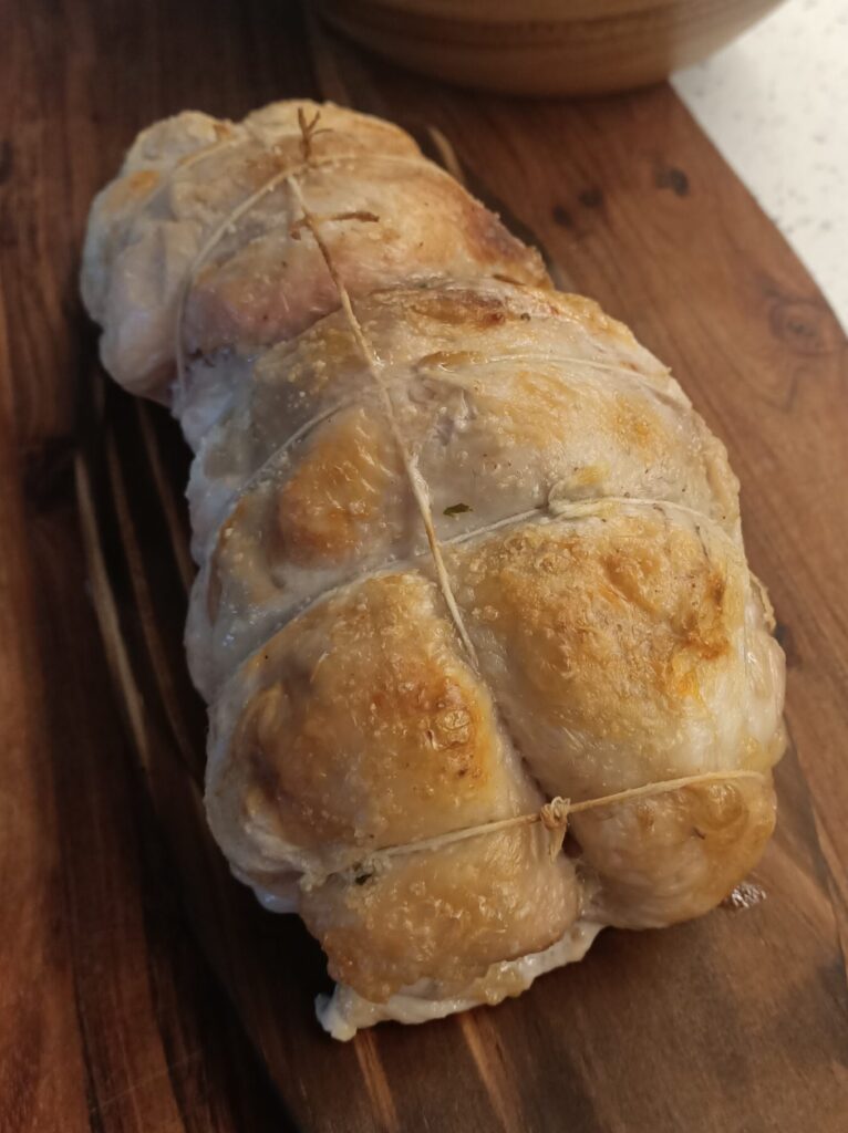 photo of a cooked and trussed piece of poultry on a wooden board