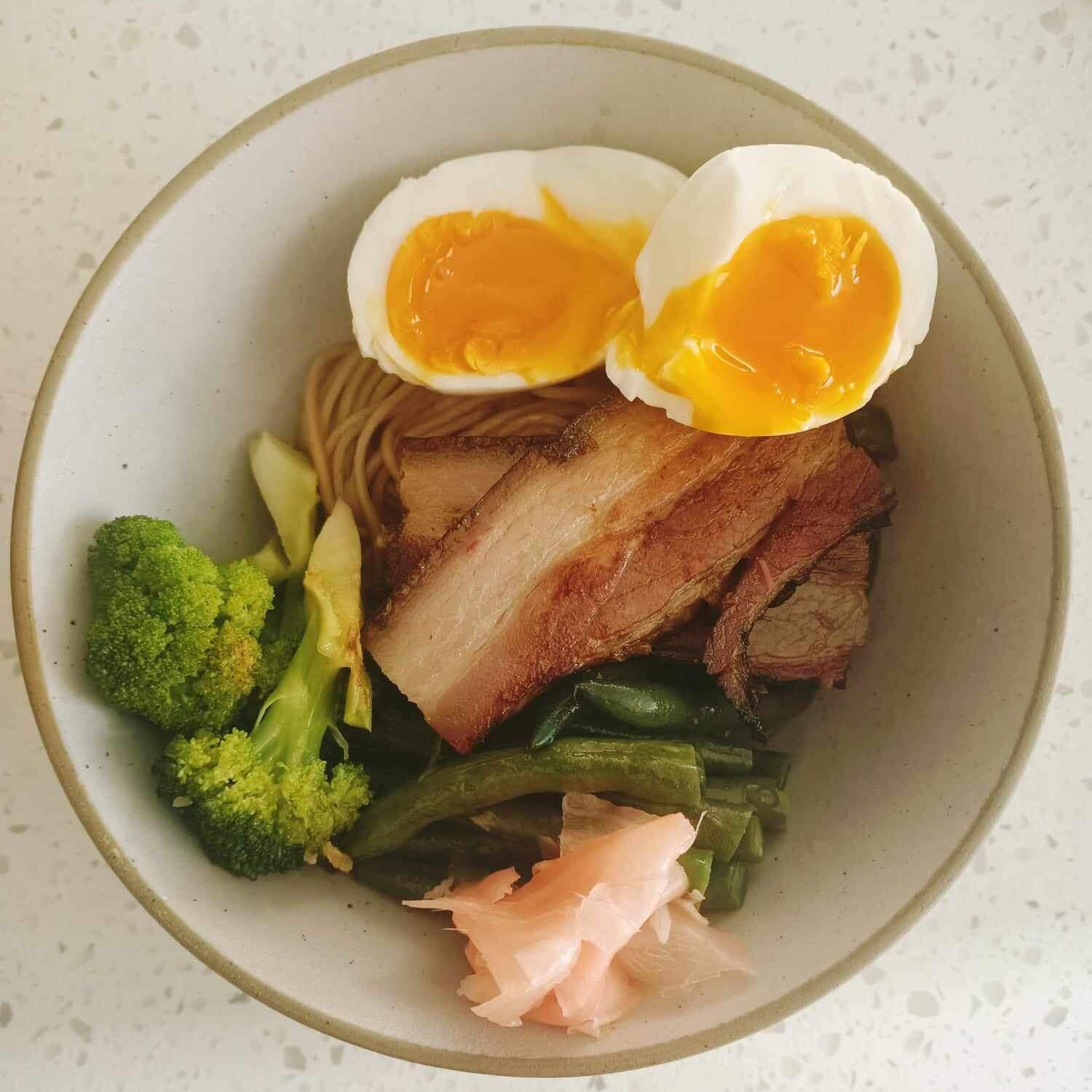 photo of a bowl with slices of meat, an egg cut in half and some vegetables