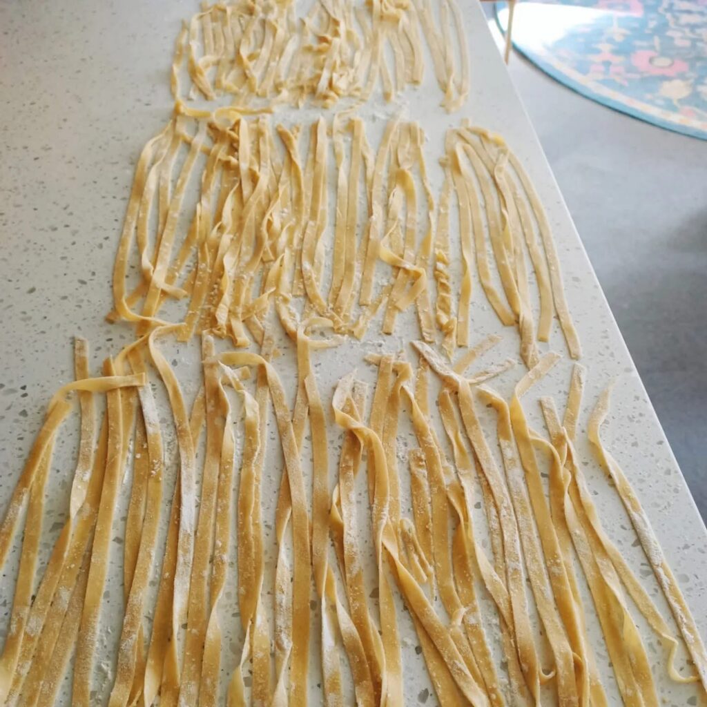 photo of strands of pasta on a white bench