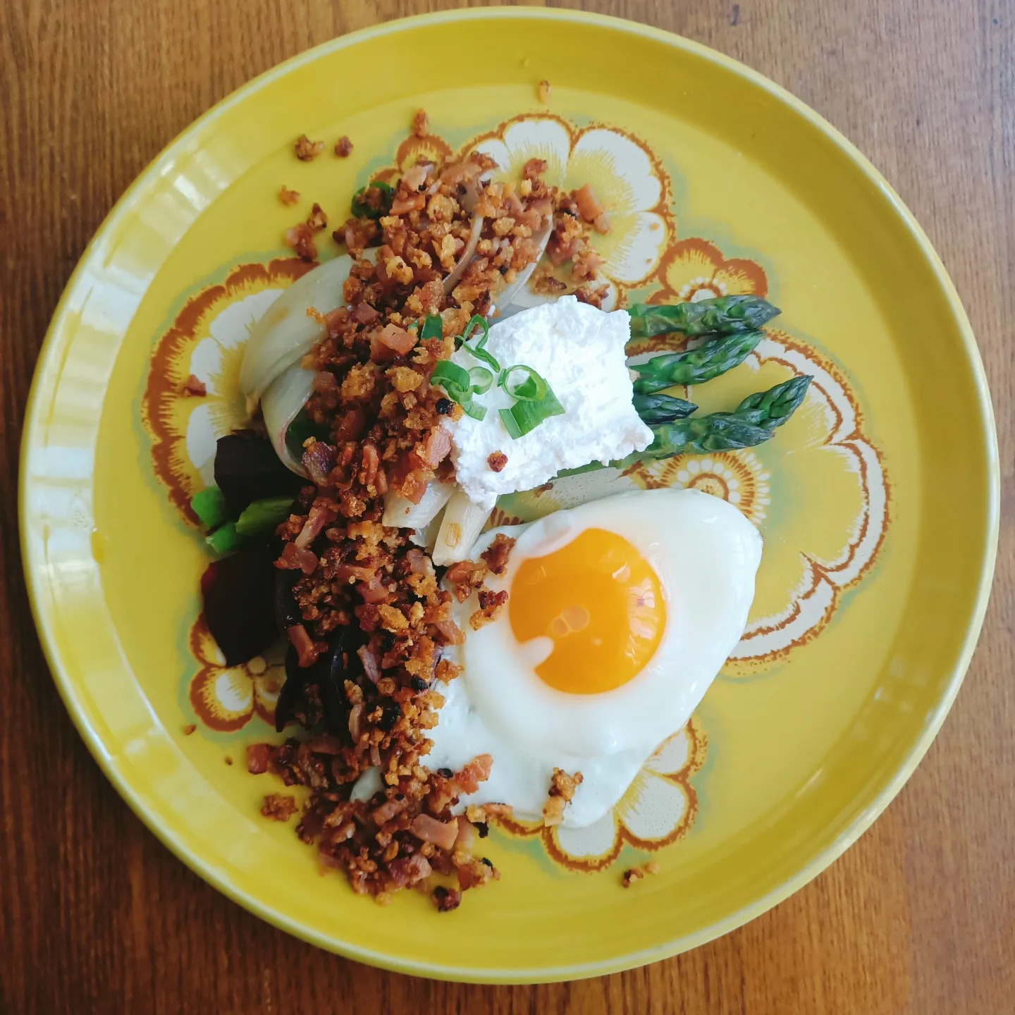 yellow plate with egg and asparagus with some kind of crumb on top