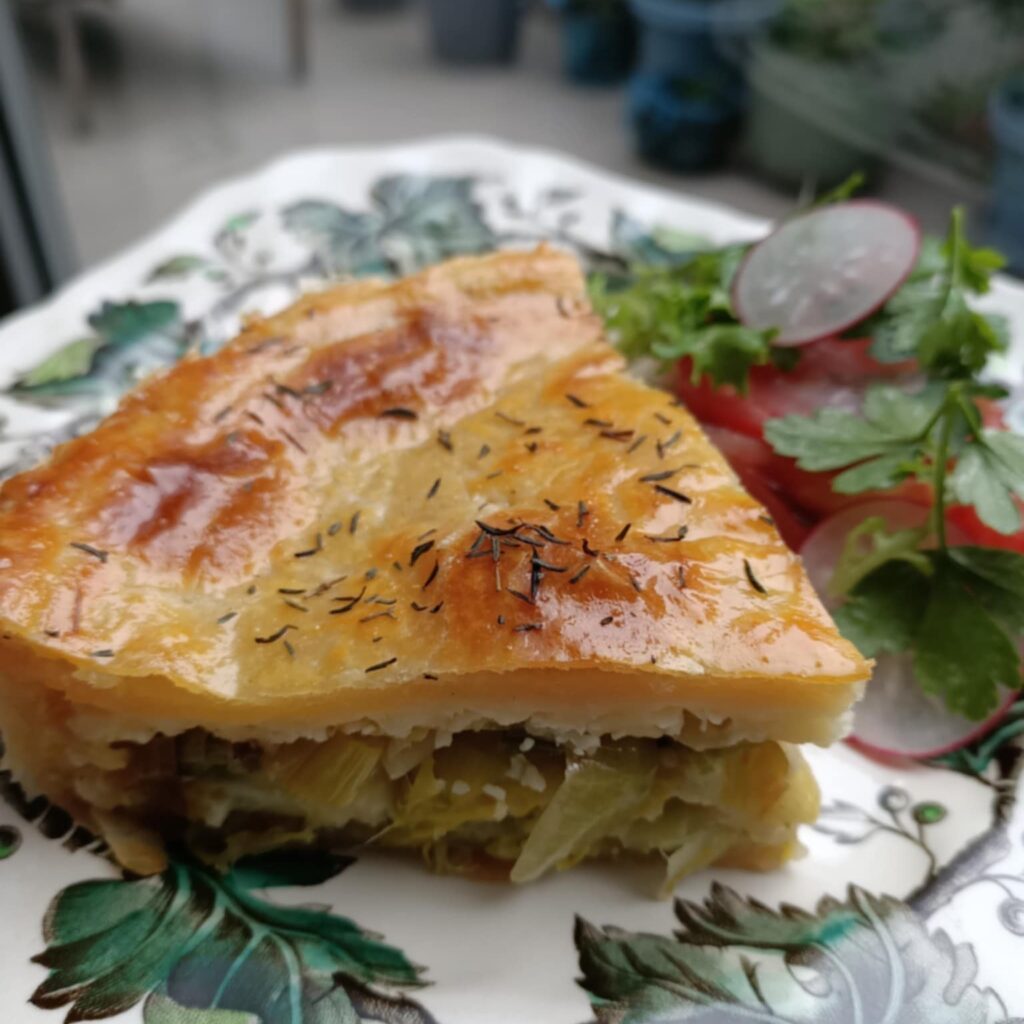 slice of pie on a floral plate with salad in the background