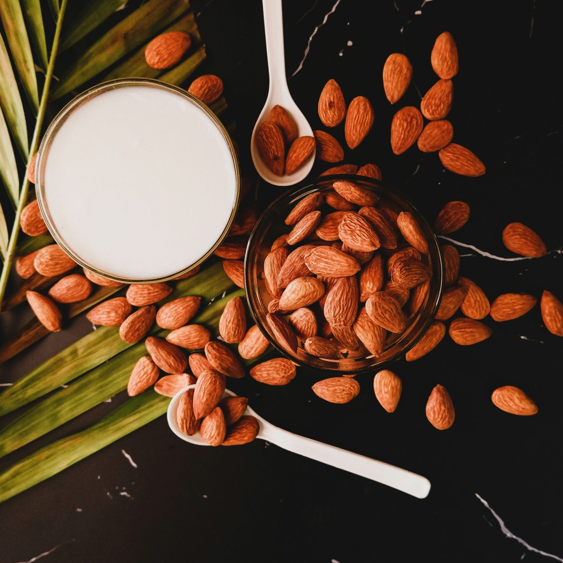 photo of almond nuts on a black background with a couple of spoons