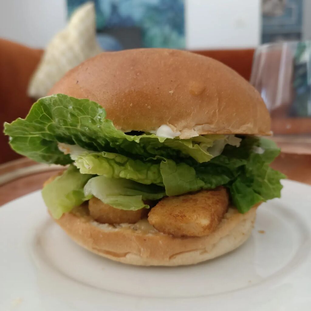 photo of a crumbed food, lettuce in a bun like a burger