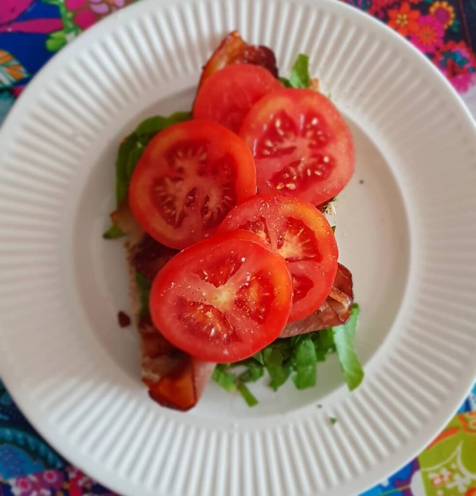 white plate with a lettuce and tomato on toast