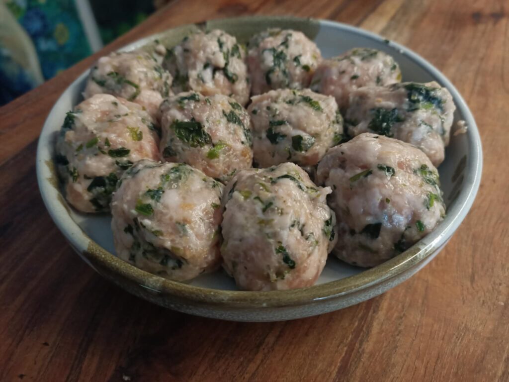 close up photo of cooked pork meatballs with flecks of green